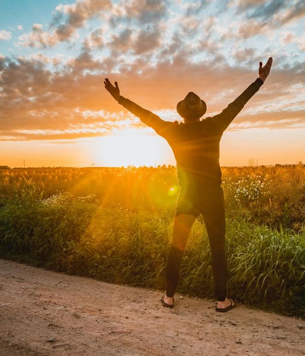 Silhouette of a person meditating at sunrise with a calm landscape.